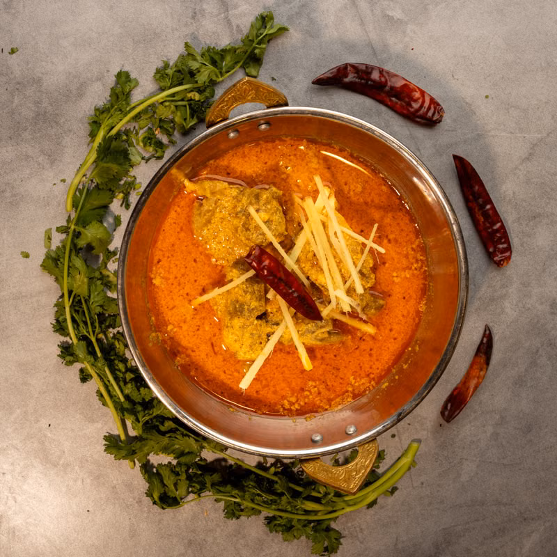 Slow-cooked meat curry garnished with ginger and coriander